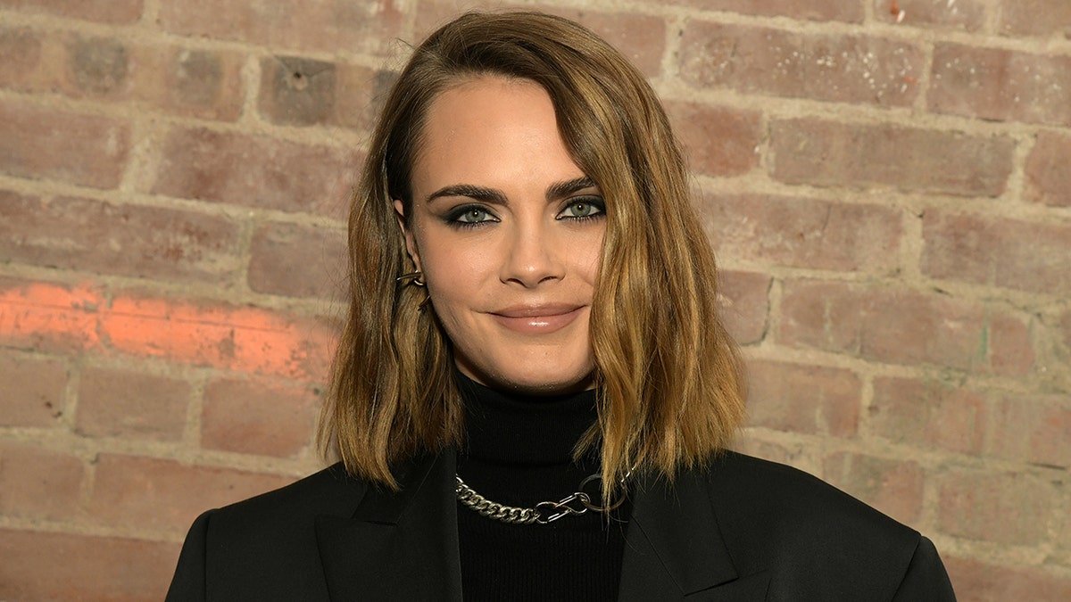 Cara Delevingne soft smiles in a black turtleneck at an event in New York City