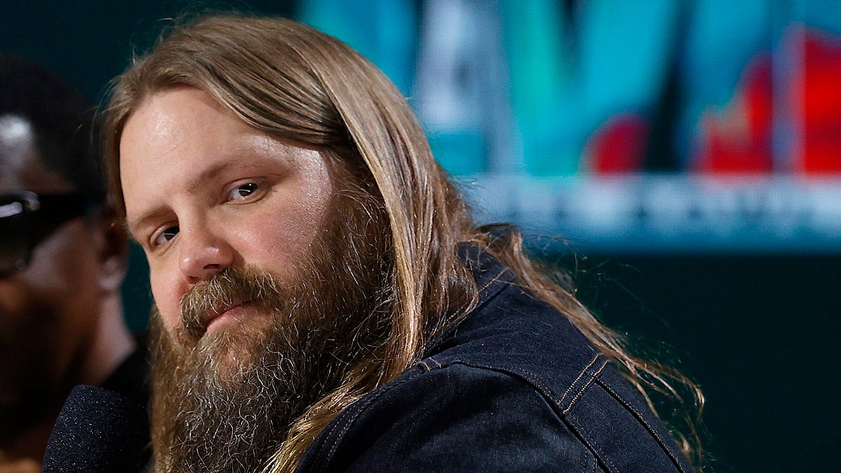 Chris Stapleton looks back at the audience as he holds the microphone during a press conference
