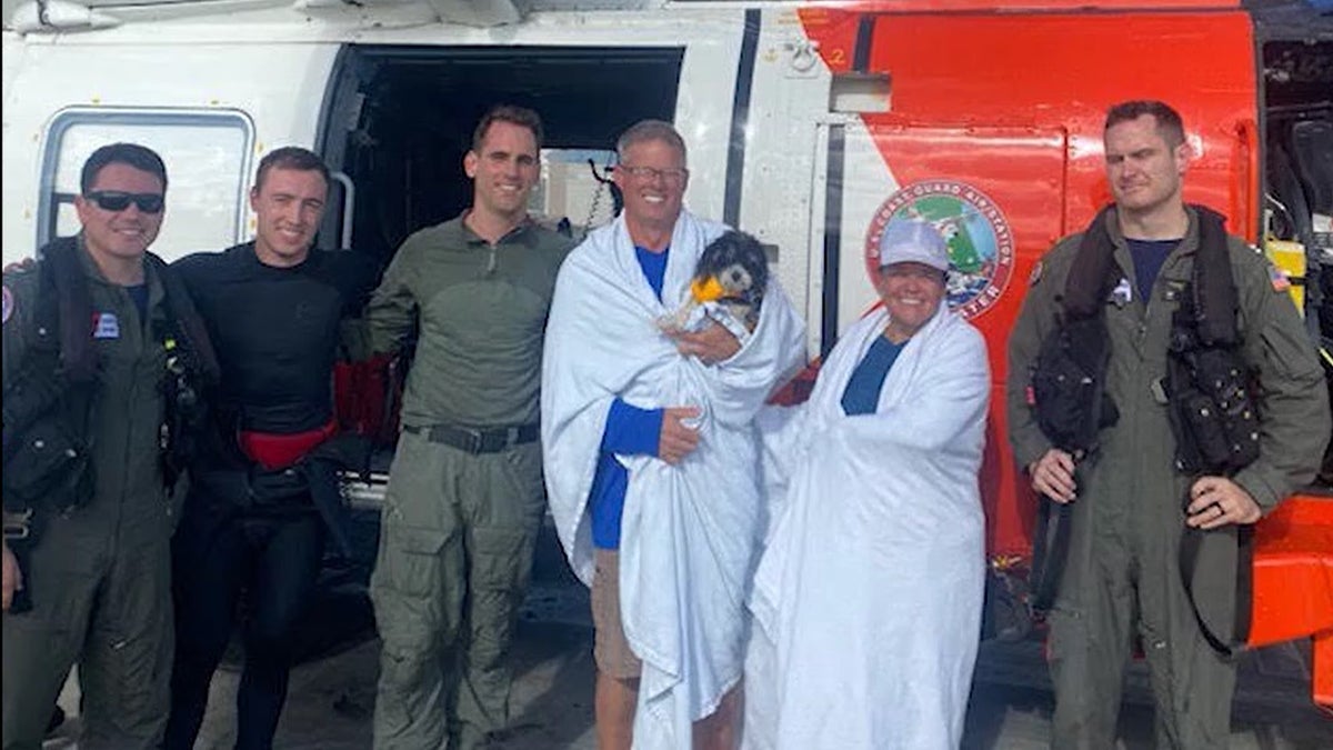 U.S. Coast Guard rescuers are pictured with the couple and dog they saved