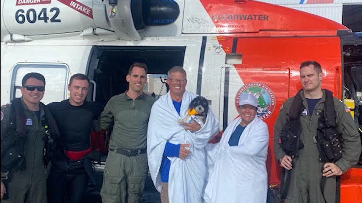 U.S. Coast Guard rescuers are pictured with the couple and dog they saved