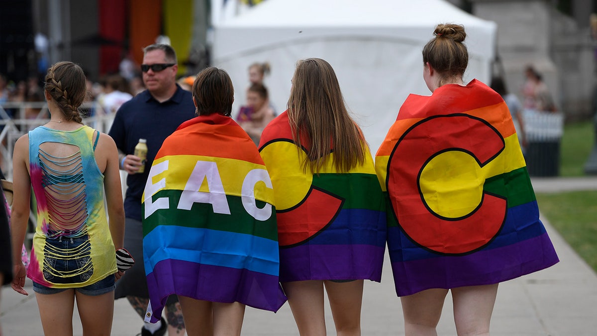 Women draped in pride flags walk