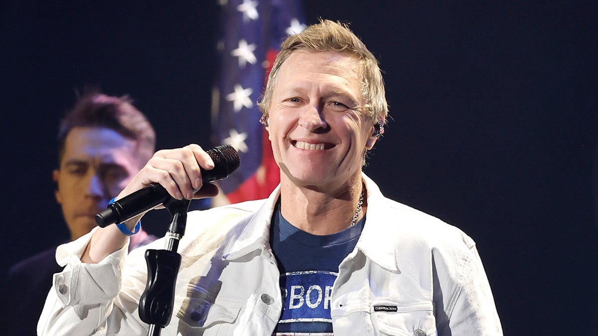 Craig Morgan sings on stage wearing white coat and blue shirt