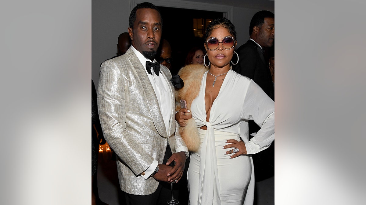 Sean Combs poses next to Misa Hylton at his 50th birthday party, both in white