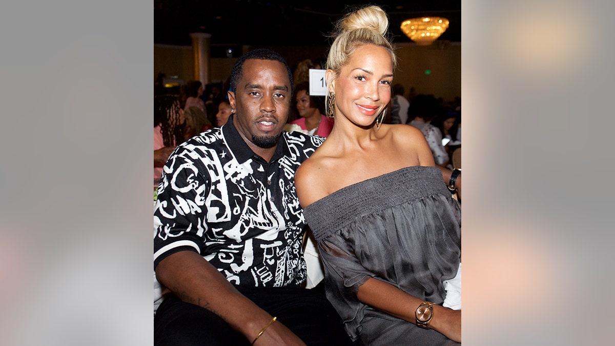 Sean Combs in a black and white printed shirt sits next to Sarah Chapman in a grey off the shoulder top