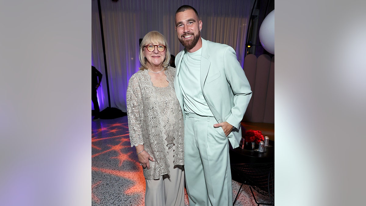 Donna Kelce in a grey lacy cardigan and pants smiles with Travis Kelce in a mint green suit