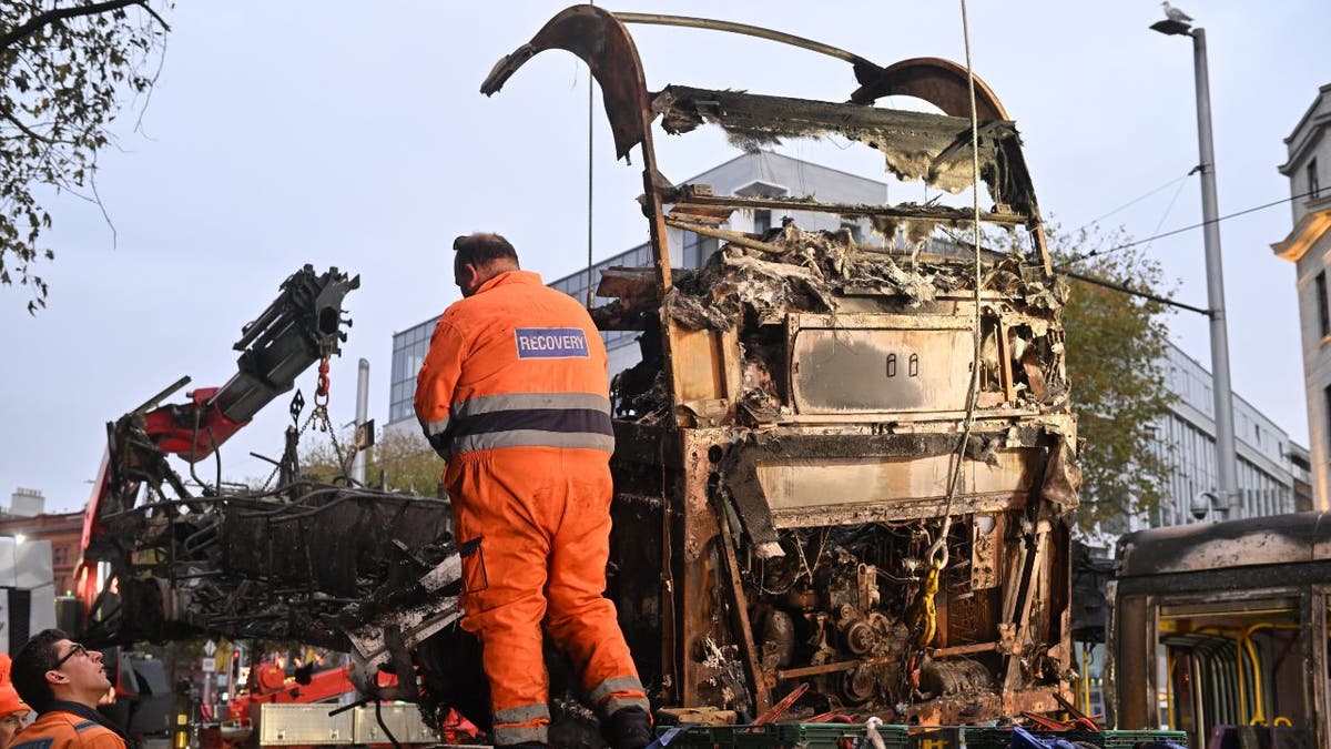 Workers remove a burnt bus in Dublin following a night of violence