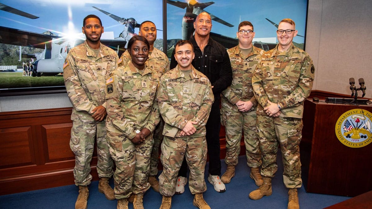 Dwayne Johnson taking a photo with service members
