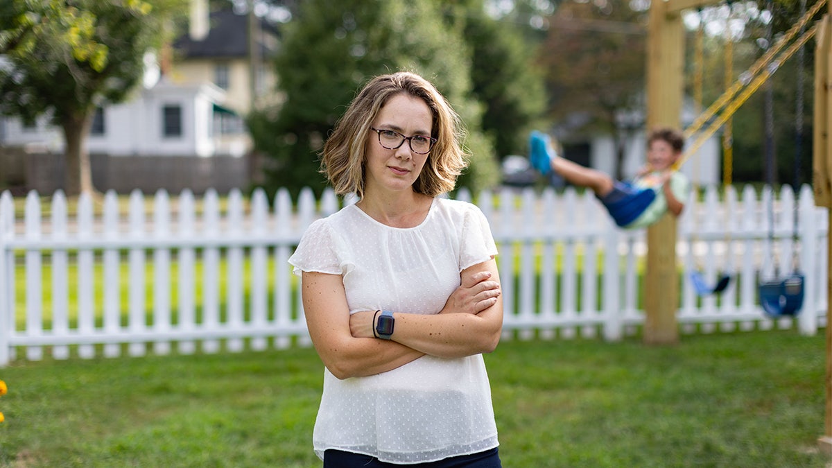 Hannah Lovaglio stands in yard as son swings on playset behind her