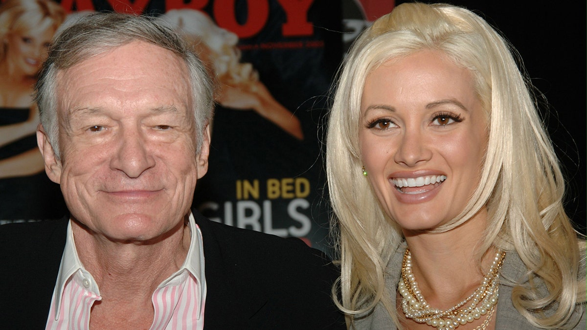 Hugh Hefner soft smiles ont he carpet with Holly Madison