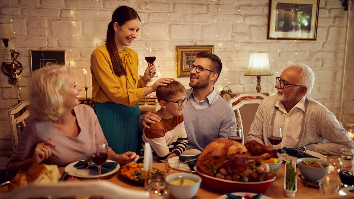 Een zoon zit op de schoot van zijn vader terwijl de familie samenkomt op het Thanksgiving-feest.