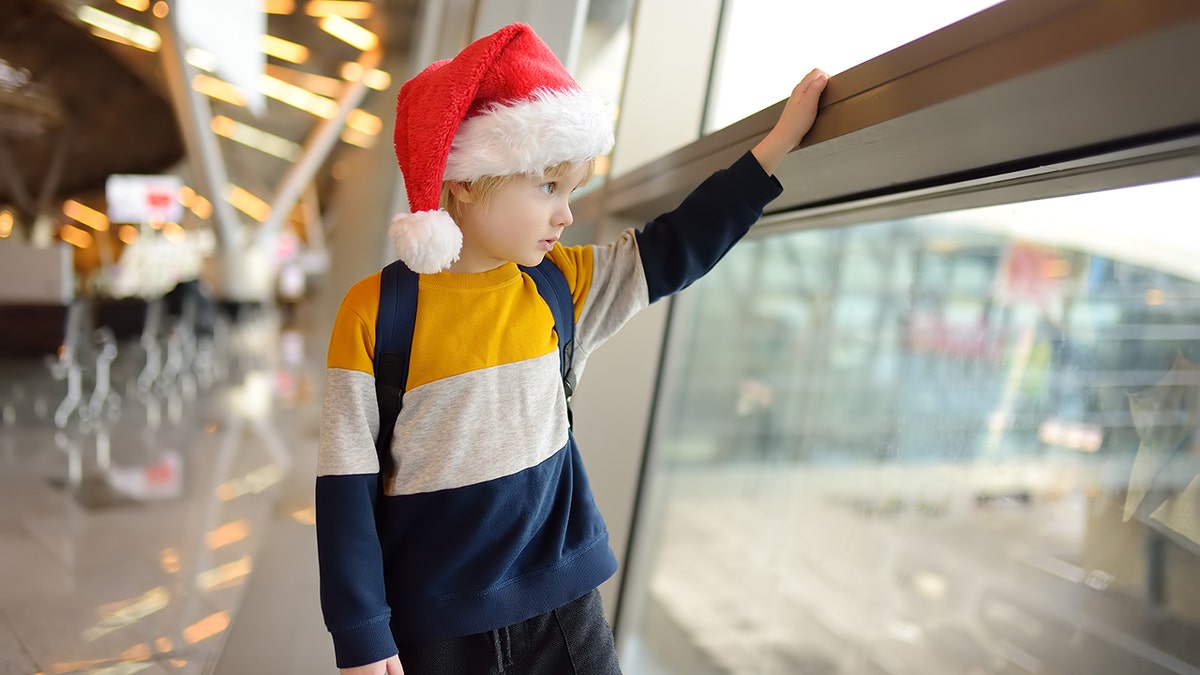 young boy in santa hat in airport