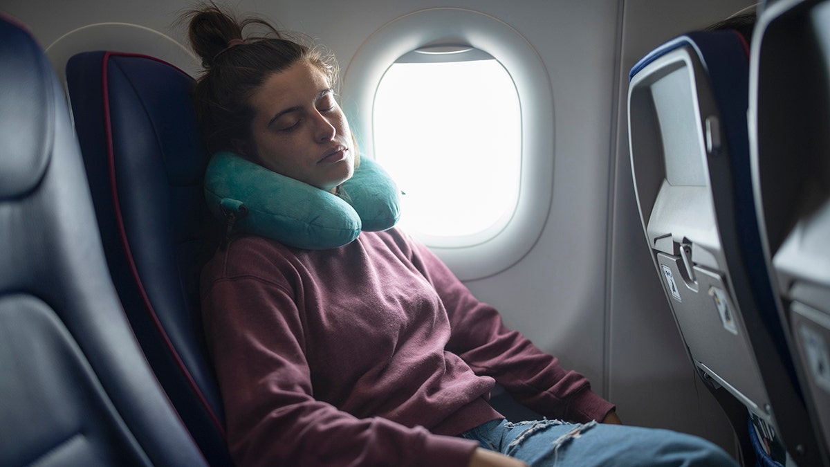 man with neck pillow on flight