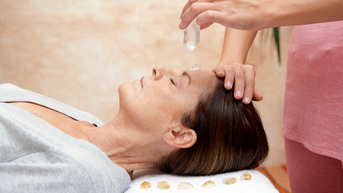 woman lying on table receiving crystal healing