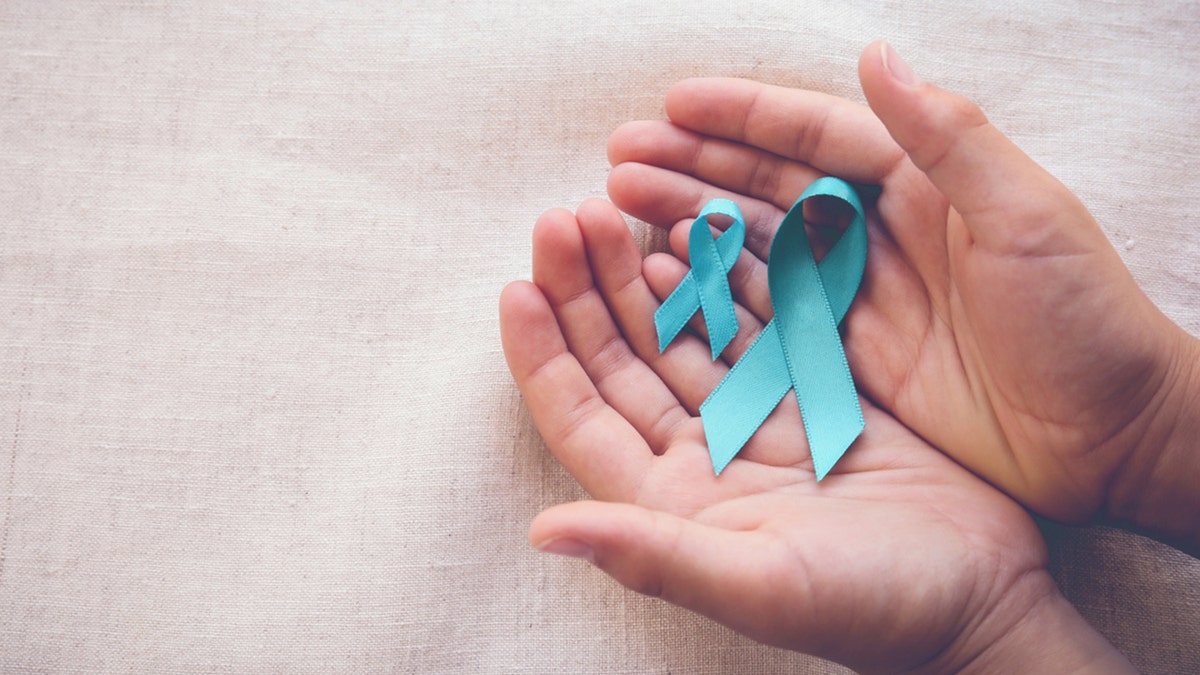 Hands holding teal ribbons for ovarian cancer awareness