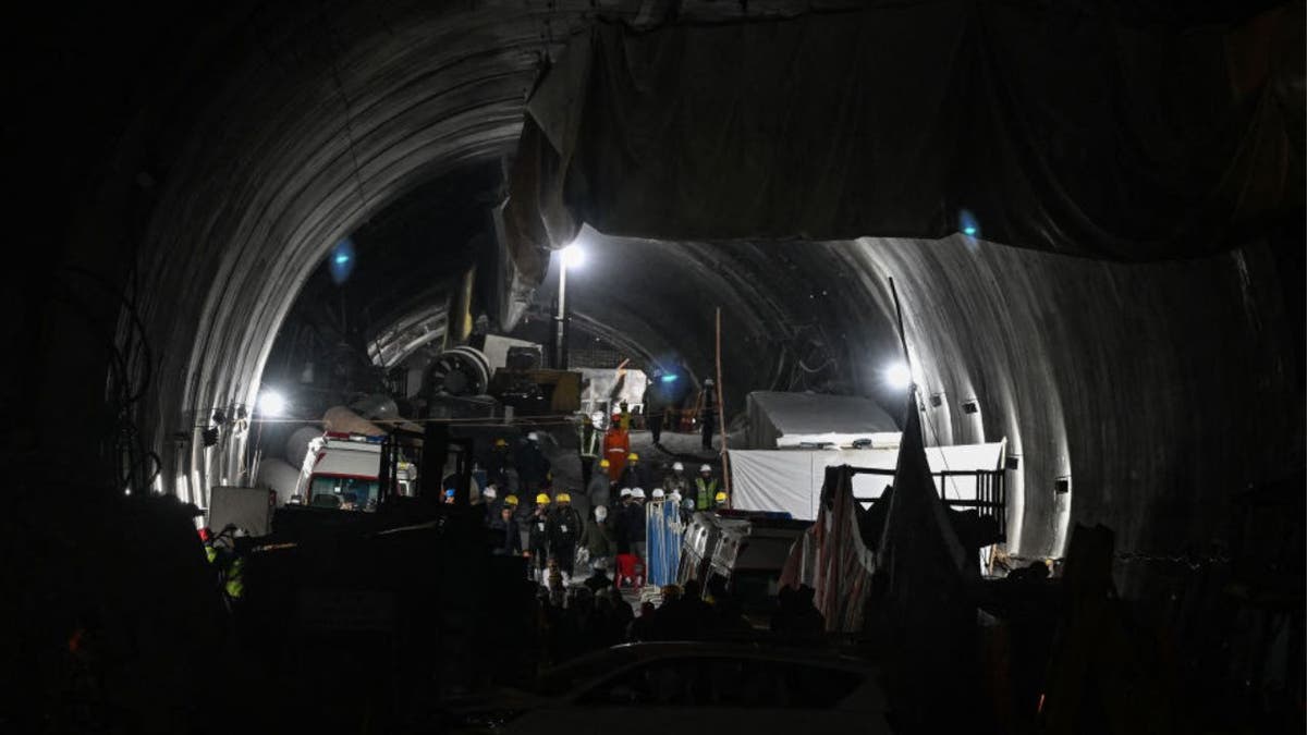 A nighttime shot of rescue personnel and officials gather at the entrance of the Silkyara tunnel in India during a rescue operation for trapped workers