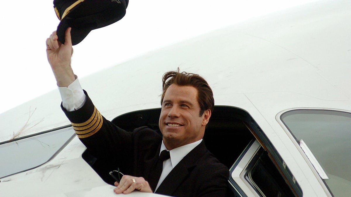 John Travolta waves captain's hat from cockpit