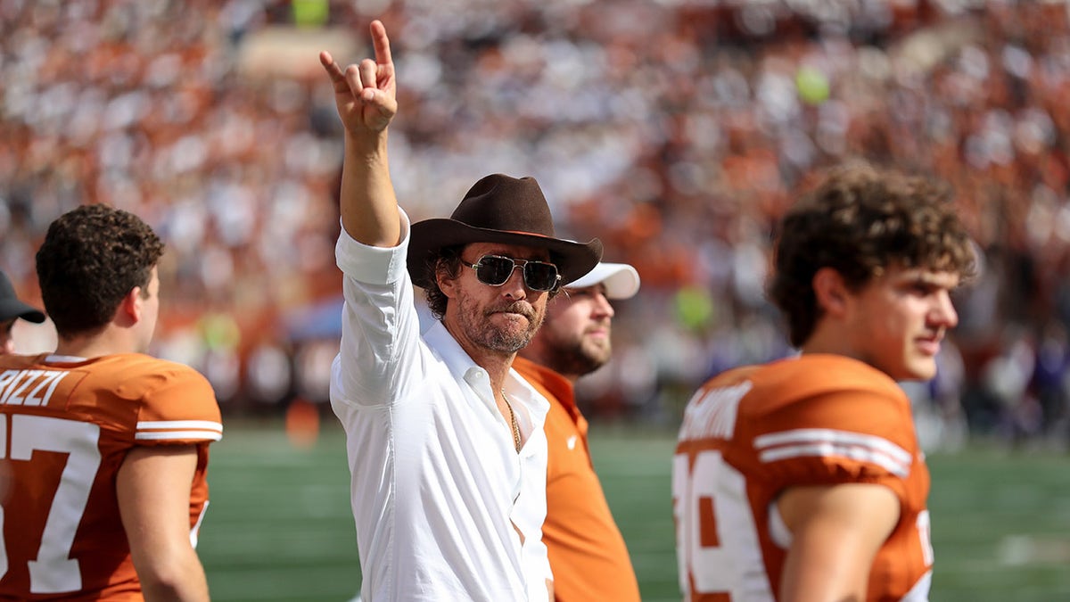Matthew McConaughey waves his hand in the air at University of Texas game