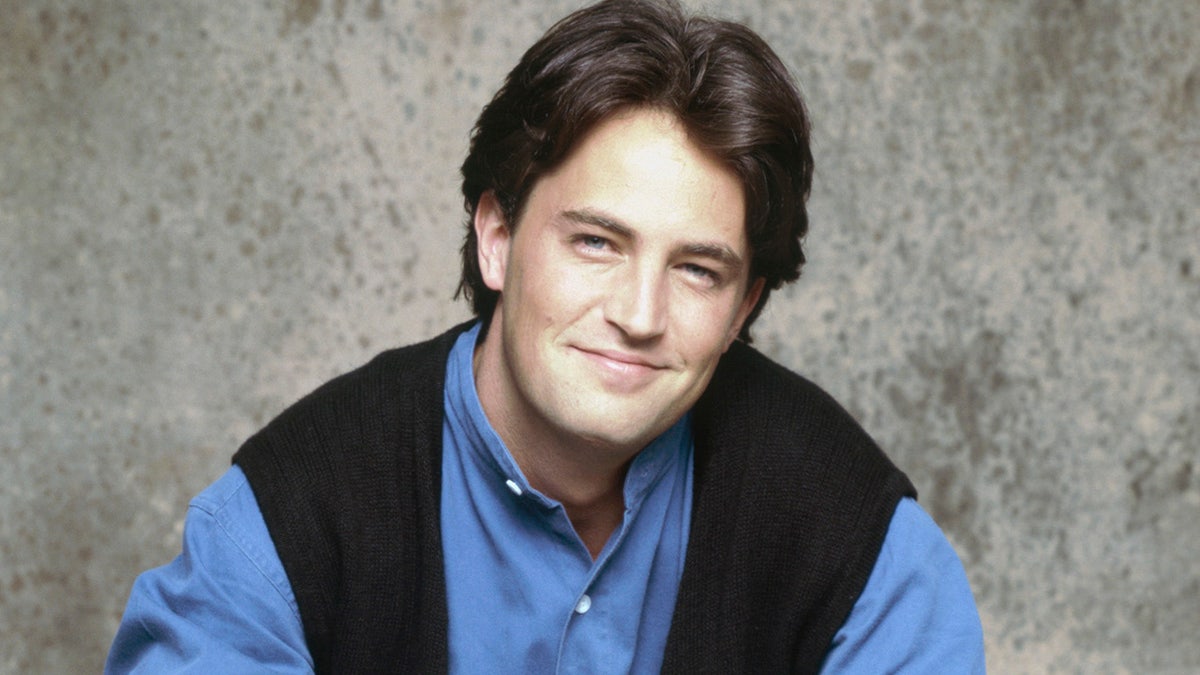 Matthew Perry wears a denim shirt and vest in a portrait photo