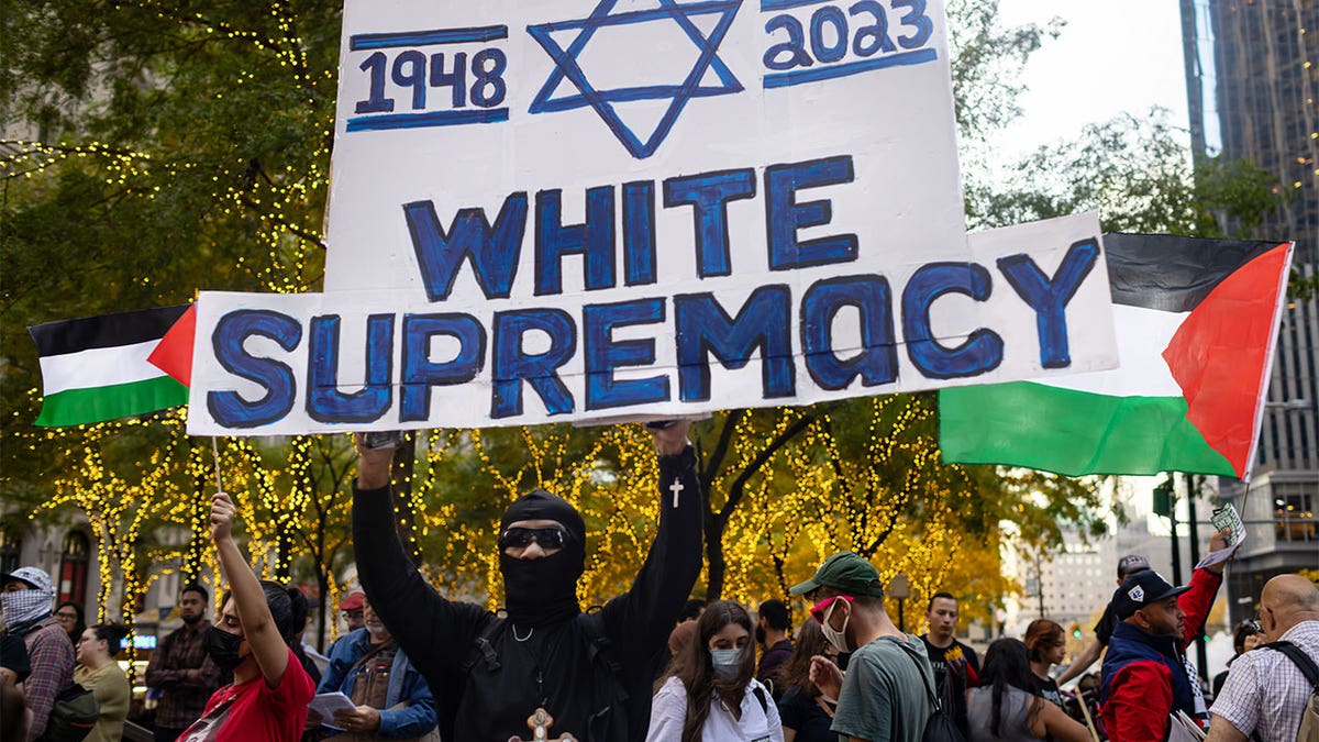 masked protester holds sign with star of David and caption "white supremacy" 1948-2023