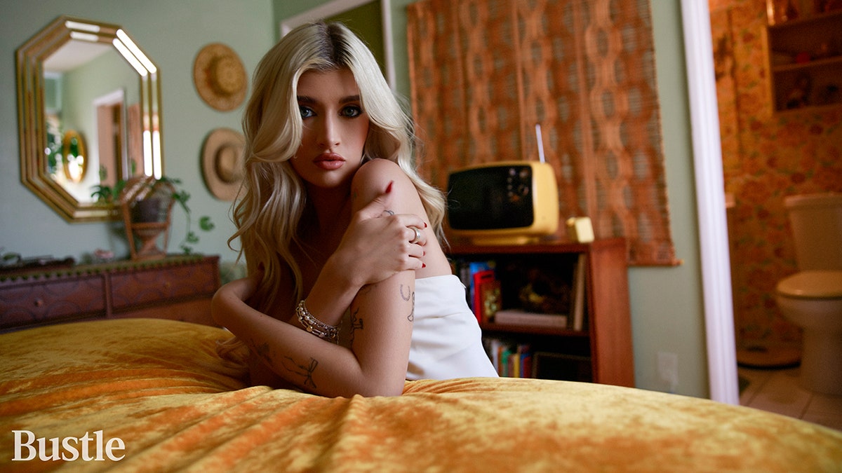 Sami Sheen in a white tube top hugs her arms for a photo taken by Bustle