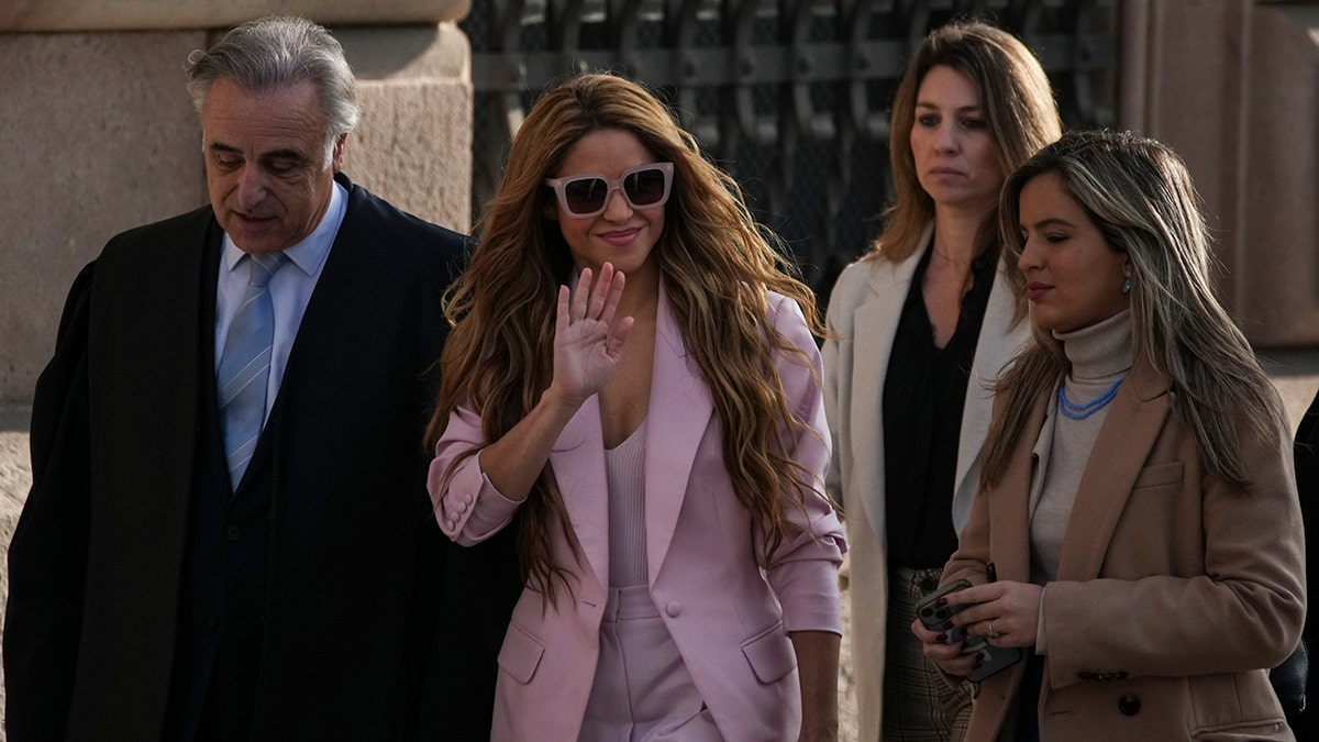Shakira in a pink suit waves to fans outside the Barcelona courthouse