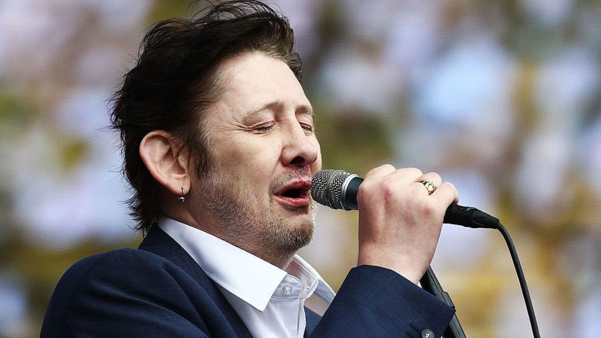 Singer Shane MacGowan singing into a microphone