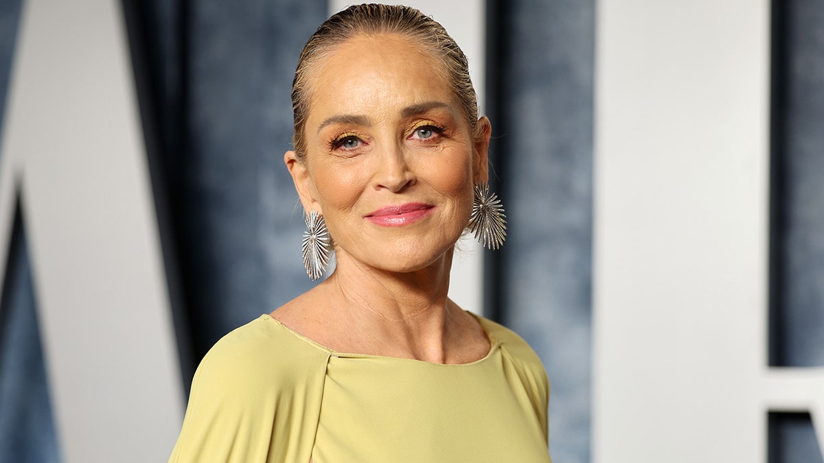 Sharon Stone in un abito giallo a maniche lunghe sorride dolcemente sul tappeto di Vanity Fair