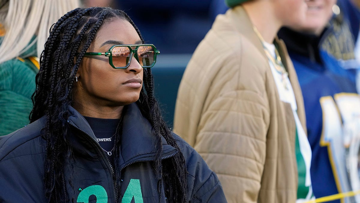 Simone Biles looks on from the sideline