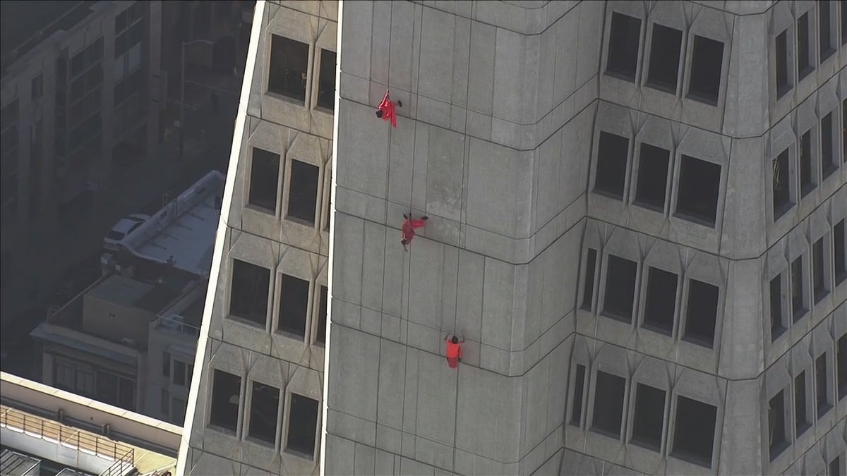The dance performers dressed in orange seen from a distance on the Transamerica Pyramid building