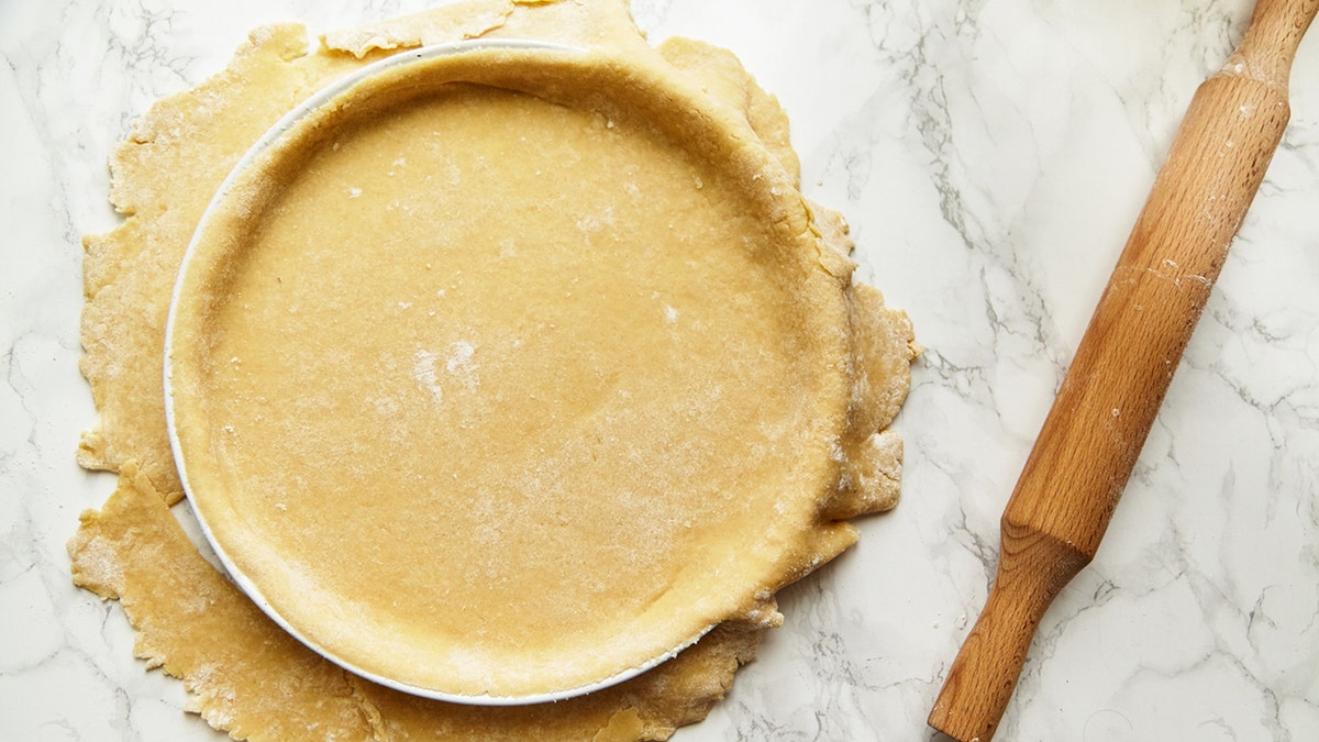 Rolling a pastry for baking a pie and pricking it with fork. Recipe concept