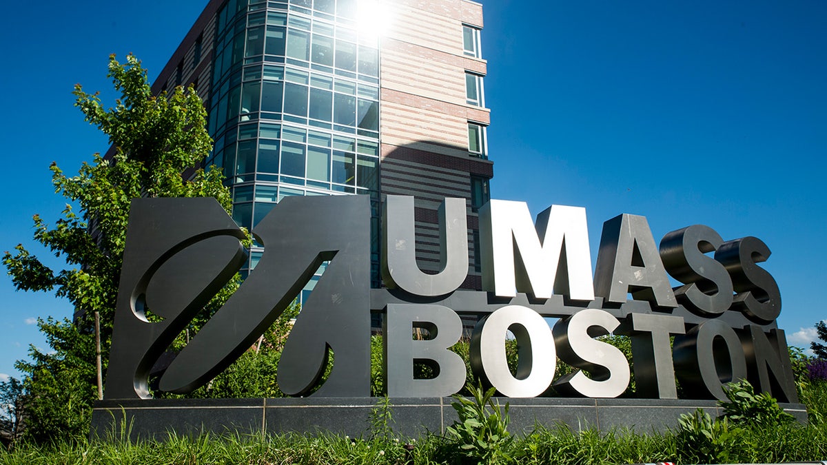Light catches on a building behind the UMass Boston sign