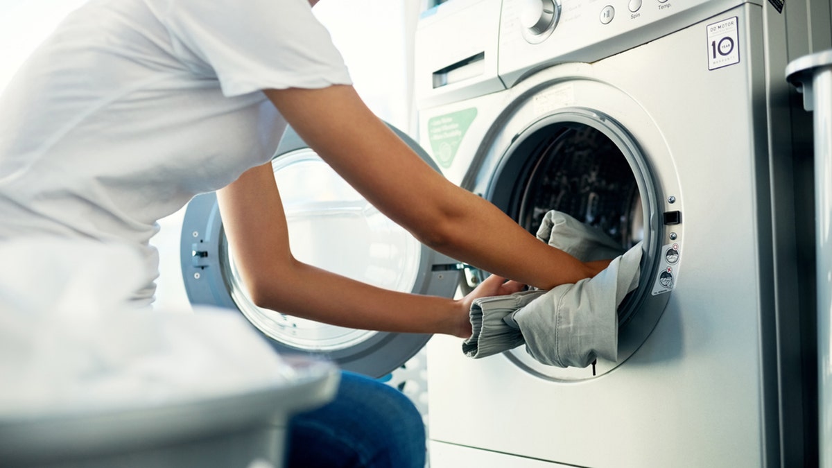 woman putting clothes in washing machine