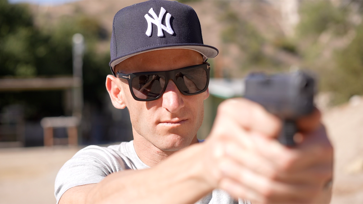 Vince Ricci in Yankees cap holding gun
