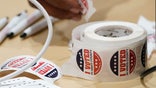 A Jackson, Miss., precinct worker reaches for more "I Voted" stickers, Tuesday, Nov. 7, 2023. All voters are given a sticker when they receive their paper ballot. (AP Photo/Rogelio V. Solis)