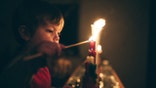 A cute little boy lights a row of candles for the Advent season, a time of remembrance and reflection on the coming birth of Jesus Christ and the Christmas season.