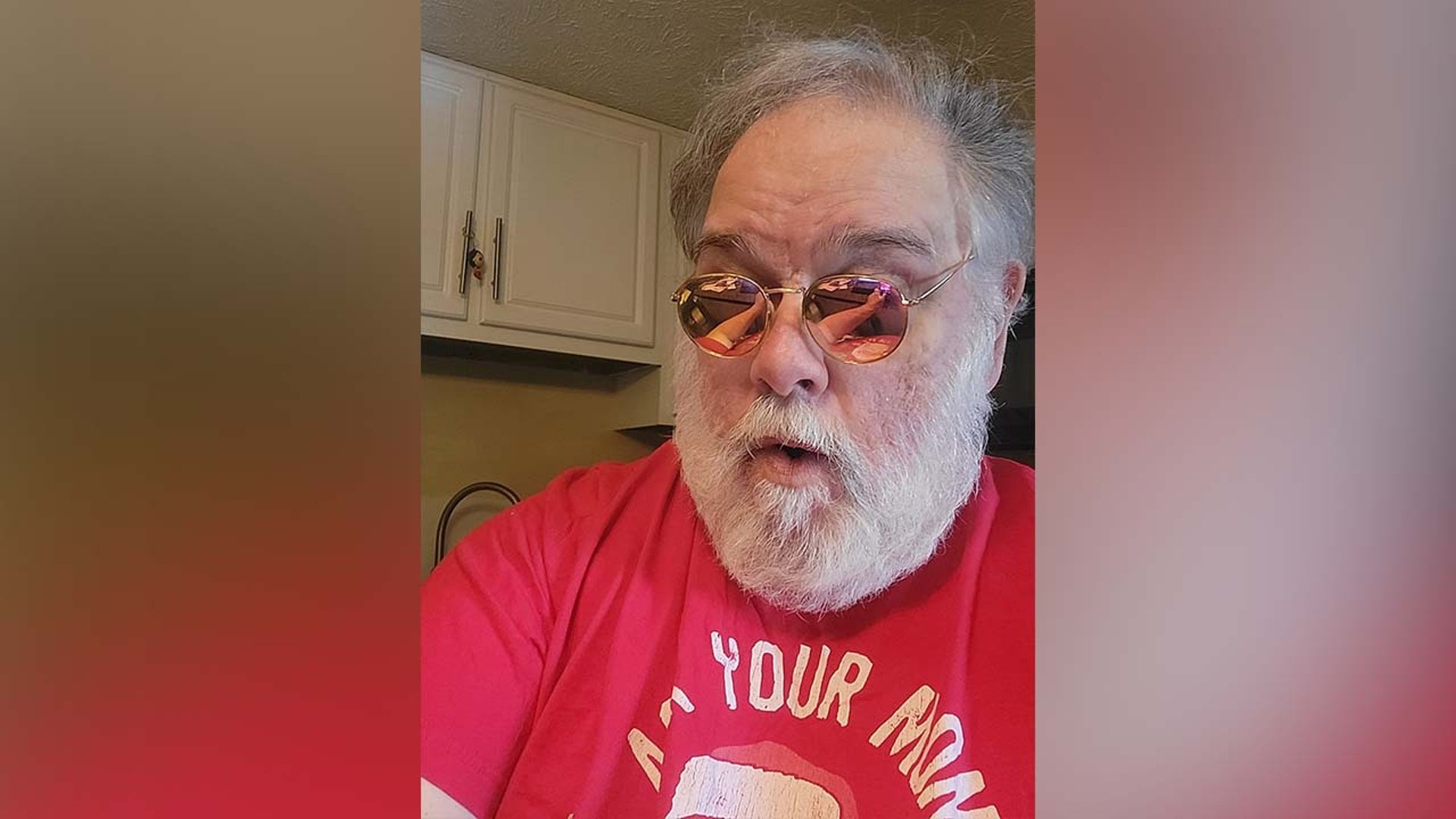 Peter Spellos laughs wearing sunglasses and red shirt