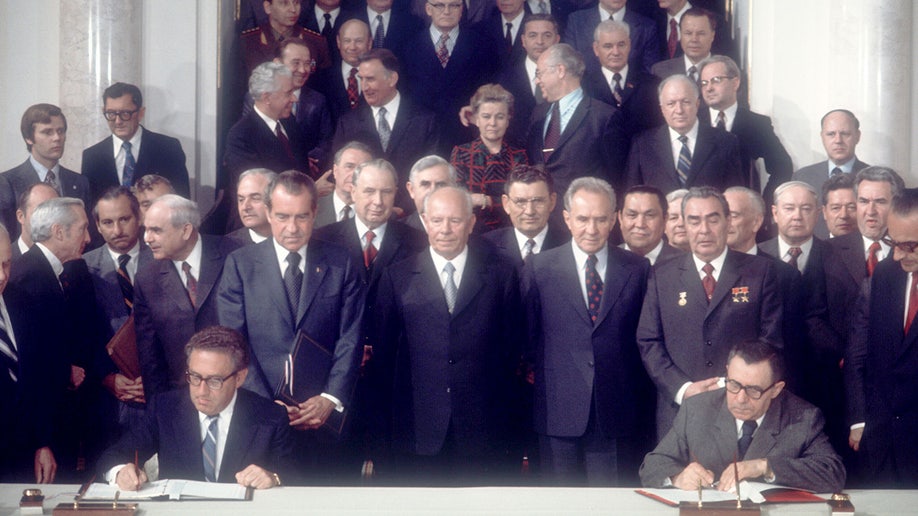 President Richard Nixon and Russian leader Leonid Brezhnev watch as US Secretary of State Henry Kissinger signs the treaty
