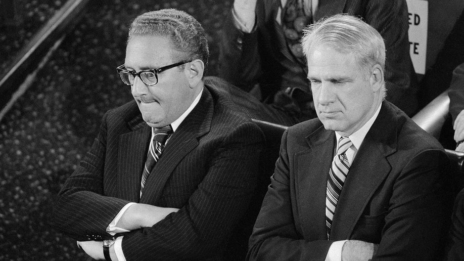 Henry Kissinger and James Schlesinger sit beside each other