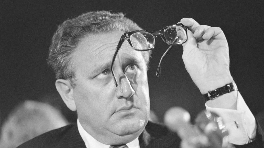 Henry Kissinger checks his glasses