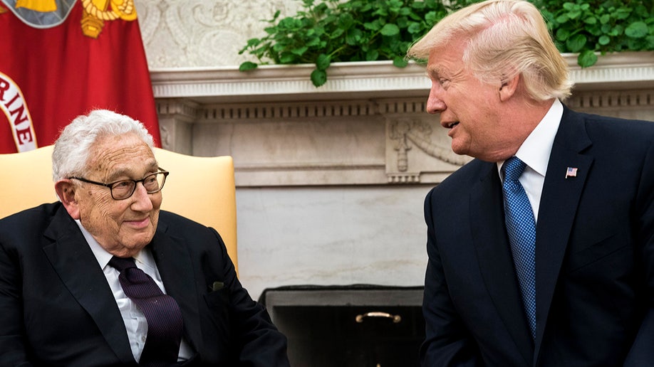Donald Trump speaks with Henry Kissinger in the Oval Office.