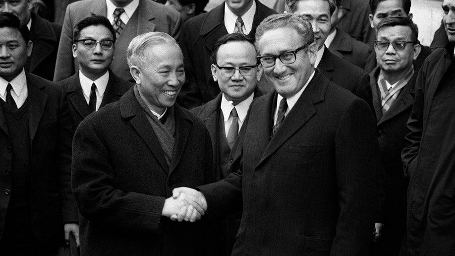 Henry Kissinger shakes hand with Le Duc Tho