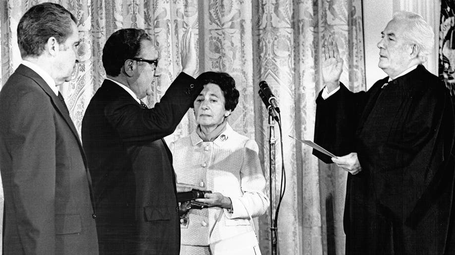 Richard Nixon watches as Henry Kissinger is sworn-in