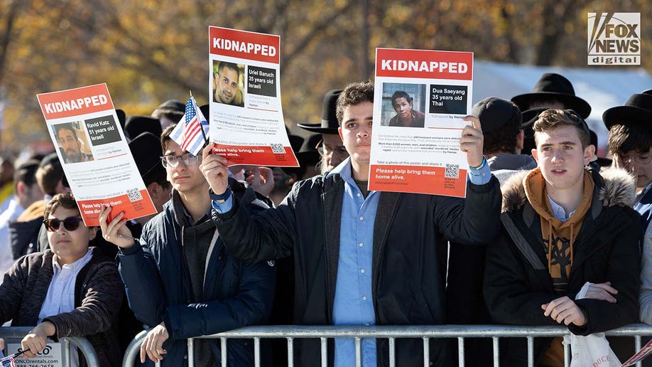 Demonstrators hold signs showing Israeli hostages kidnapped by Hamas at the March for Israel