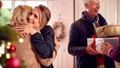 Couple Greeting Senior Parents As They Arrive With Presents To Celebrate Christmas