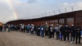 JACUMBA HOT SPRINGS, CALIFORNIA - NOVEMBER 30: Asylum seeking migrants wait in line to receive donated food, with a rainbow in the distance, at a makeshift camp while awaiting processing by the U.S. Border Patrol on November 30, 2023 in Jacumba Hot Springs, California. The remote community, with a population of 600, has seen a recent influx of hundreds of immigrants arriving daily and sheltering in makeshift camps in the desert cold as they await transfer to established U.S. Border Patrol detention centers with limited capacity.