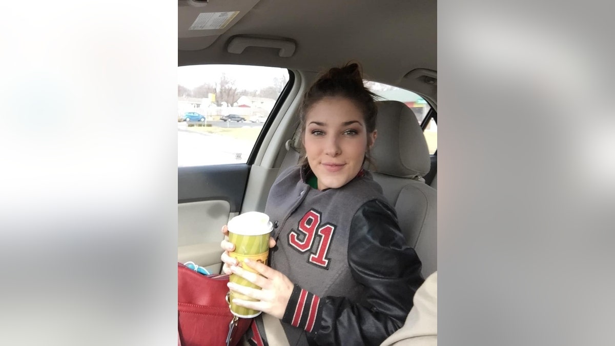 Libby Caswell holds a to-go coffee cup in a car