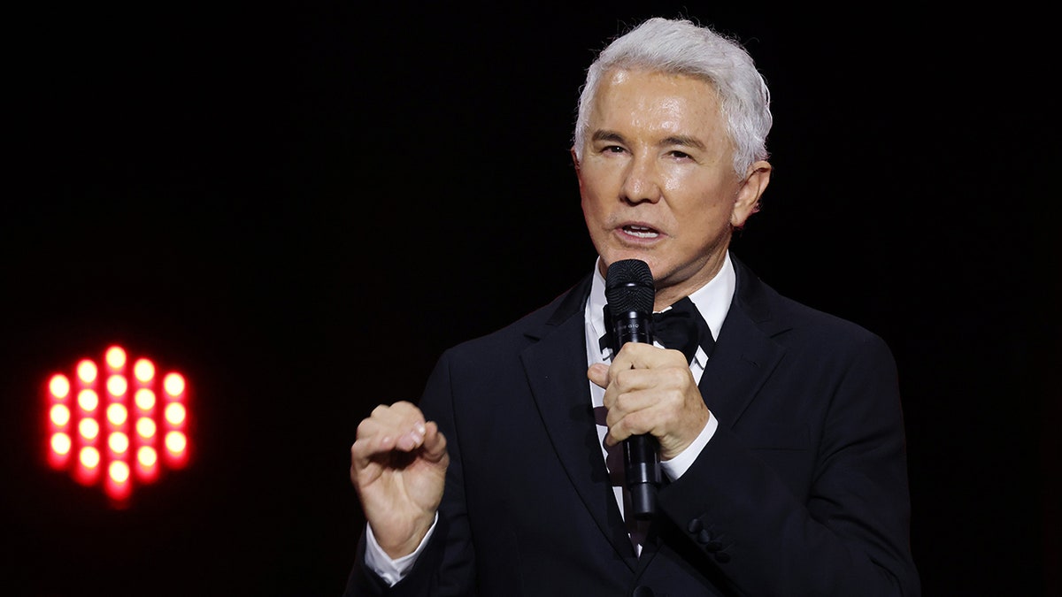 Baz Luhrmann on stage holding a microphone