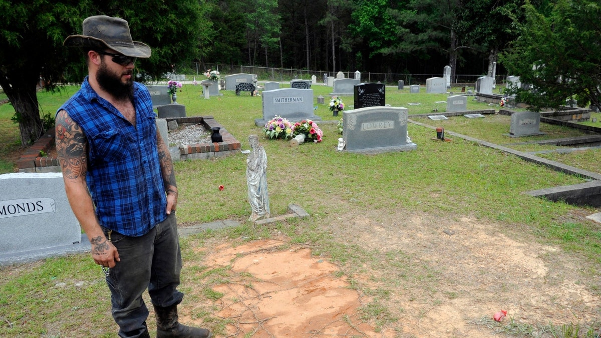 Tyler Goodson of the hit podcast "S-Town" stands at the grave in Green Pond, Ala., of his late friend John B. McLemore, who is also featured in the show, on May 3, 2017.