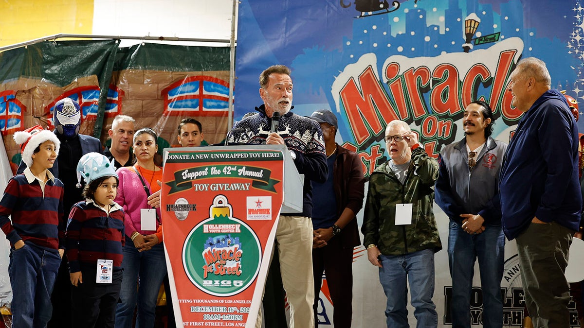 Arnold Schwarzenegger at podium giving speech at charity toy drive