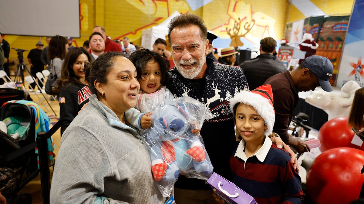 Arnold Schwarzenegger with a family at a charity toy drive